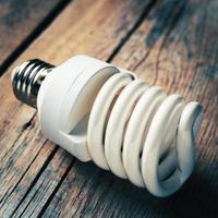 närbild av energibesparande glödlampa på träskrivbord foto