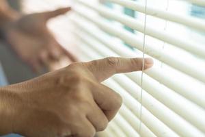 man kontroll gardiner använda sig av din fingrar till håll de gardiner på de fönster. foto