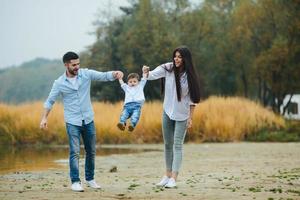 ung familj gående på de strand foto