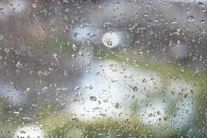 regn droppar på fönsterruta och suddig bakgrund foto