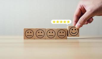 användare väljer till Betygsätta de service 5 stjärnor smiley ansikte ikon på trä- blockera. begrepp efter försäljning service och kommentarer. tillfredsställelse, Bra och imponerande. excellent företag betyg, rykte foto