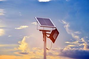 mini sol- eller solceller cell panel installerad på metall Pol med strålkastare led, blurr molnig och blå himmel bakgrund, begrepp för använder sig av naturlig energi från de Sol i dagligen liv av mänsklig. foto