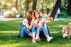 två kvinna vän Sammanträde i de parkera ha en resten ta en selfie foto