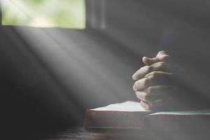 hand vikta i bön till Gud på helig bibel bok i kyrka begrepp för tro, andlighet och religion, kvinna person bön- på helig bibel i morgon. kristen katolik kvinna hand med bibel dyrkan. foto