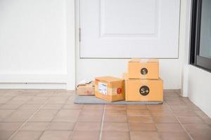 kartong paket låda nära dörr på golv. uppkopplad handla, lådor levereras till din främre dörr. lätt till stjäla när ingen är Hem. paket i kartong låda på tröskel. leverans service foto