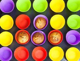 fyra muffins och många tömma flerfärgad formar foto