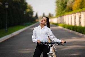 skön flicka Framställ på vit cykel. promenad i natur. foto