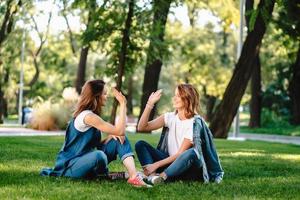 Lycklig kvinna vänner höjning händer upp ger hög fem i stad parkera foto