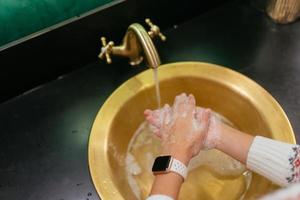 stänga upp Foto av kvinna tvättar henne händer med tvål och vatten.