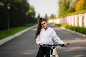 skön flicka Framställ på vit cykel. promenad i natur. foto