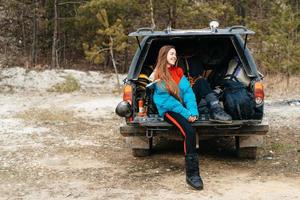 ung kvinna njuter natur medan Sammanträde i de bil trunk foto
