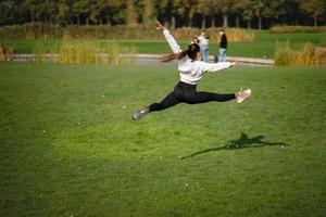 sport flicka Hoppar i de luft på natur demonstrera perfekt stretching. foto