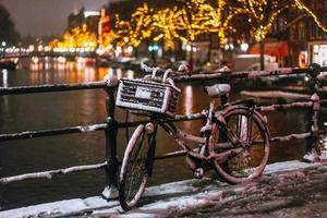 cyklar parkerad längs en bro över de kanaler av amsterdam foto