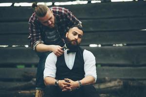barberare rakar en skäggig man i vintage atmosfär foto