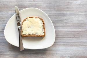 smörgås med Smör och kniv på vit tallrik foto