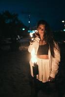 ung kvinna med fackelsken på de strand på natt foto