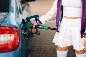 kvinna fyllning henne bil med bränsle på en gas station foto