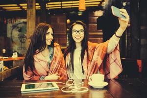 två stänga vänner göra selfie i de Kafé foto