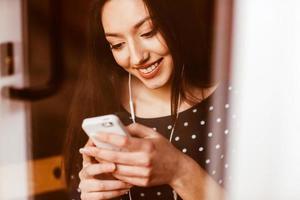 skön flicka lyssnande till musik på de telefon och leende. Instagram toning effekt foto