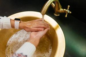stänga upp Foto av kvinna tvättar henne händer med tvål och vatten.