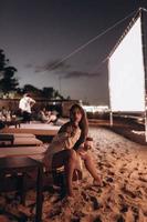 ung kvinna är Sammanträde på stol på natt strand foto