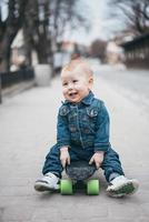 liten rolig pojke med skateboard på de gata foto