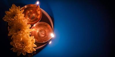 diwali indisk Semester. traditionell diya olja lampor och gul blommor på blå bakgrund. fira festival av ljus. foto