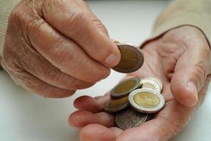 pensionerad äldre kvinna räkning mynt pengar och oroa handla om en gång i månaden kostnader och behandling avgift betalning. foto