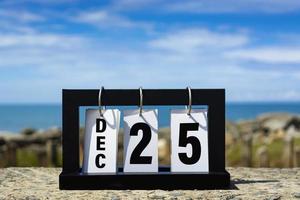 dec 25 kalender datum text på trä- ram med suddig bakgrund av hav. foto