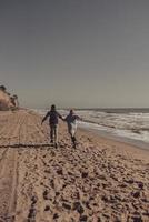 man och kvinna njut av varje Övrig, springa längs de havsstrand foto