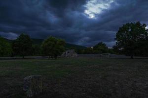 mörk molnig landskap i arkeologi webbplats, gammal stad i en lantlig miljö med roman ruiner i de bakgrund, molnig kväll i roman välde övergiven gammal stad foto