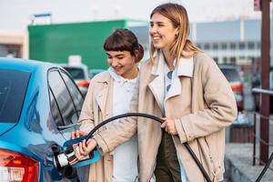 Lycklig vänner tanka bil i gas station. Semester resa foto