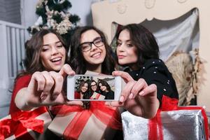 skön flicka fotograferad sig själva på de telefon på de bakgrund av jul gåvor. dekorativ årgång lägenhet. foto
