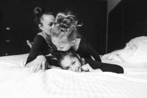 mamma och två döttrar ha roligt på de säng foto