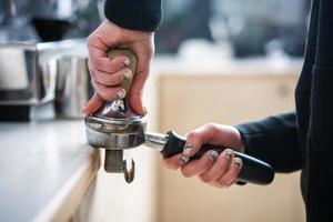 Barista trycker på jord kaffe använder sig av manipulera. foto