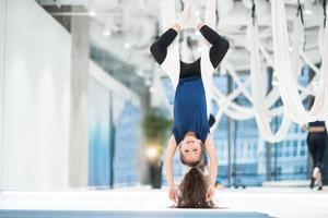 porträtt av en skön ung flicka engagerad i flyga yoga på dukar. foto