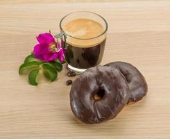 kaffe med choklad munkar på trä- bakgrund foto