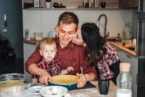 pappa, mamma och liten son laga mat en paj foto