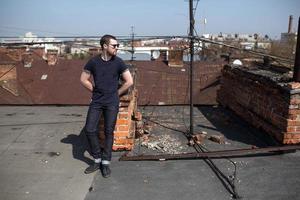 mannen i de autentiska stövlarna och jeansnaven på taket av byggnaden i gamla stan foto