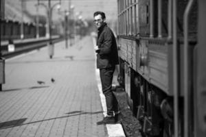 en man klädd i jeans på de bakgrund av de tåg och de station foto