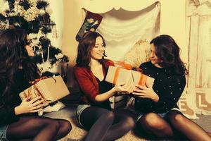 skön flicka öppning jul gåvor. dekorativ årgång lägenhet. foto