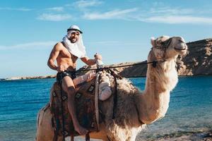 kille rider på en kamel på de strand foto