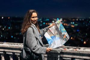 flicka med en Karta på de bakgrund av de natt stad foto