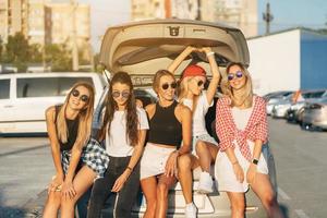 fem ung kvinnor ha roligt på de bil parkera. foto