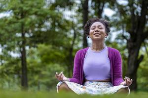 afrikansk amerikan kvinna avkopplande praktiserande meditation i de skog till uppnå lycka från inre fred visdom för friska sinne och själ begrepp foto