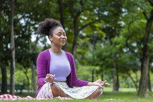 afrikansk amerikan kvinna avkopplande praktiserande meditation i de skog till uppnå lycka från inre fred visdom för friska sinne och själ begrepp foto