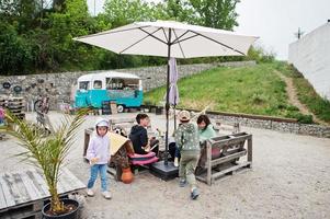 familj sitta på Kafé med mysigt små mini buss mat marknadsföra. foto