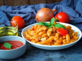 makaroner pasta med tomat sås i vit tallrik på grå Färg tabell foto