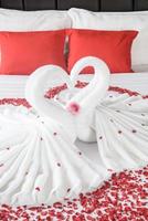 två svanar och hjärta tillverkad från handdukar på smekmånad säng foto