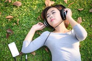 ung flicka lyssnande till musik med hörlurar i stad parkera foto